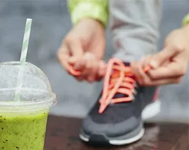 Athlete tying their shoe with a healthy drink